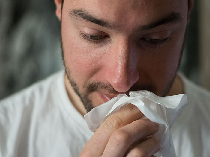 A man holding a tissue up to his nose