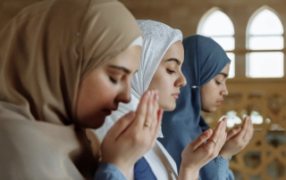 Tres mujeres musulmanas con hijab rezando juntas, una al lado de la otra